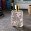 Clear perfume glass bottle decorated with custom colorful butterfly and floral pattern UV DTF decals.