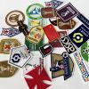 Collection of custom flock heat transfer patches and embroidered badges on white background