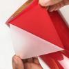 Hand peeling PET carrier film from red PU heat transfer vinyl, showing easy weeding performance
