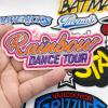 Hand holding a custom colorful "Rainbow Dance Tour" embroidered patch with heat melt adhesive backing