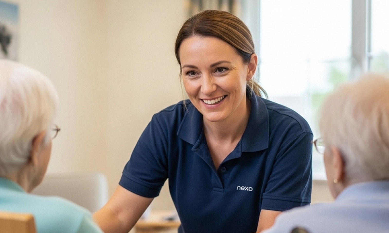Nexo People carer smiling while talking with elderly residents in a care home