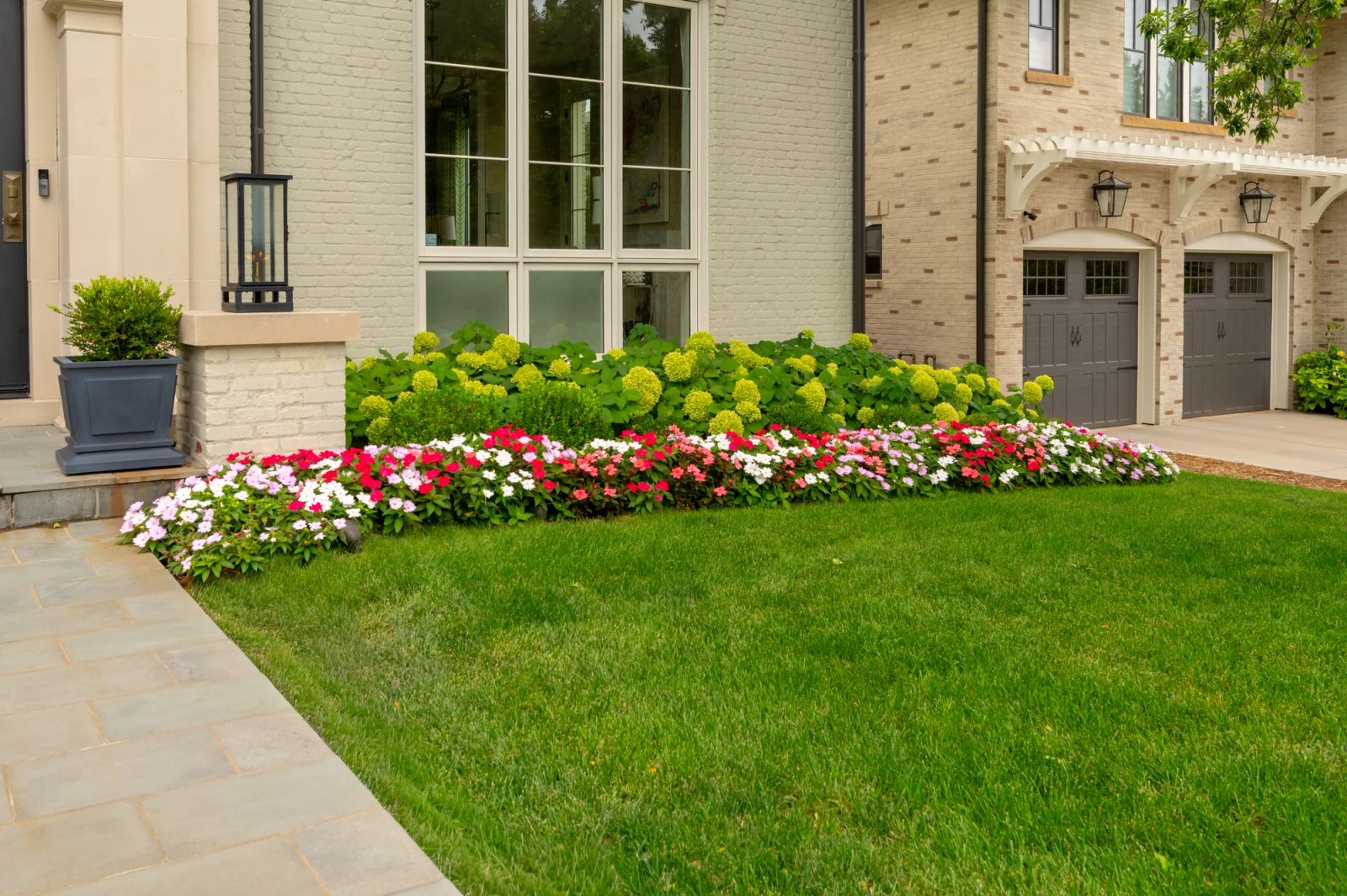 Curved front flower bed of impatiens and hydrangeas.