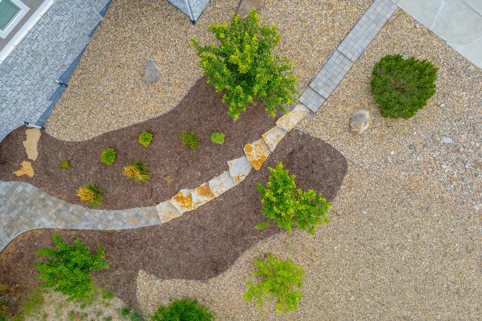 Aerial view of water-wise beds with gravel, mulch, shrubs and a stone path.