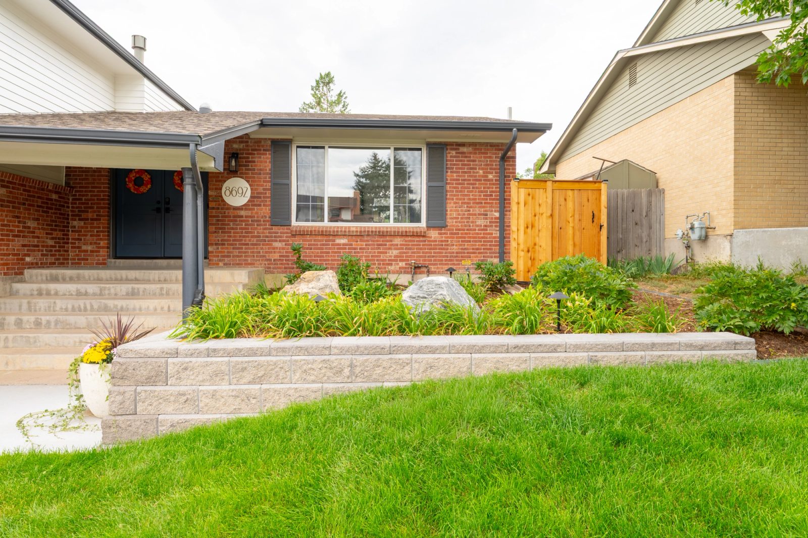 Front yard with retaining wall, garden, and fencing.