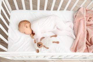 bébé qui dort dans son lit à barreaux avec son doudou