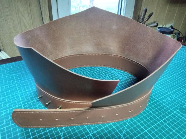 Cintura in pelle color cognac fatta a mano con bordi cuciti e fori di regolazione, su tappetino da taglio