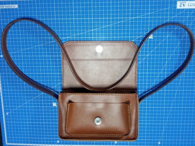 Коричнева шкіряна міні-сумка crossbody з клапаном на магніті та довгим ремінцем, фото на килимку для різання