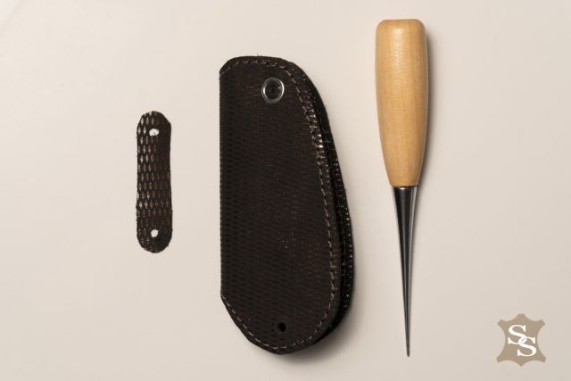 Темний шкіряний чохол для ключів із текстурою та кнопкою, ручна робота, поруч інструмент для шкіри