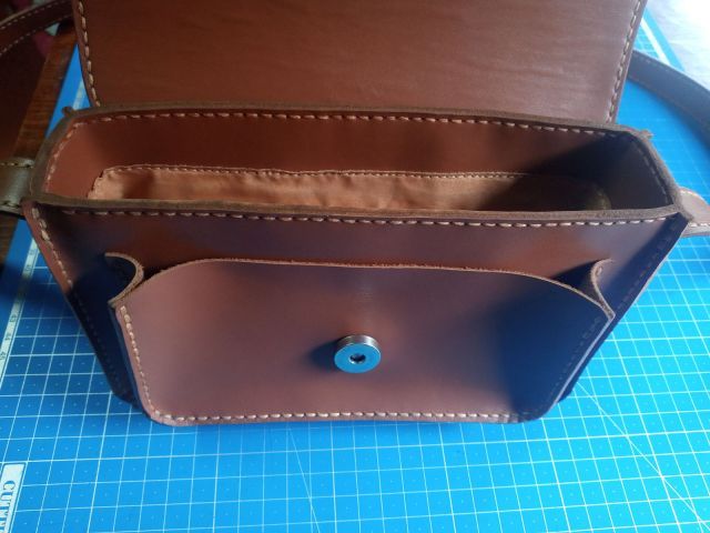 Коричнева шкіряна міні-сумка crossbody з клапаном на магніті та довгим ремінцем, фото на килимку для різання