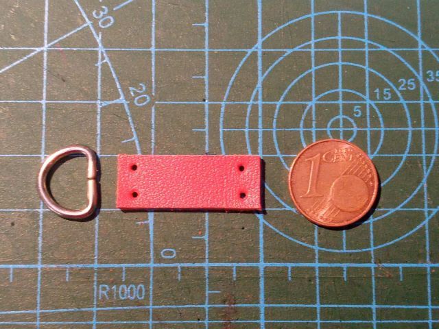 Червона шкіряна міні-сумка конверт із ремінцем та металевим ланцюжком на фоні розкрійного килимка