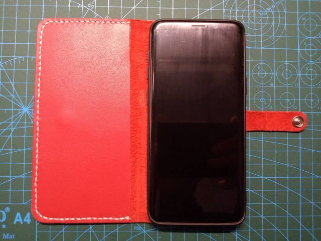 Червоний шкіряний чохол-книжка для смартфона з ремінцем на кнопці та білою строчкою, ручна робота