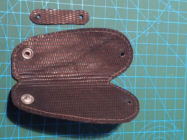 Темний шкіряний чохол для ключів із текстурою та кнопкою, ручна робота, поруч інструмент для шкіри