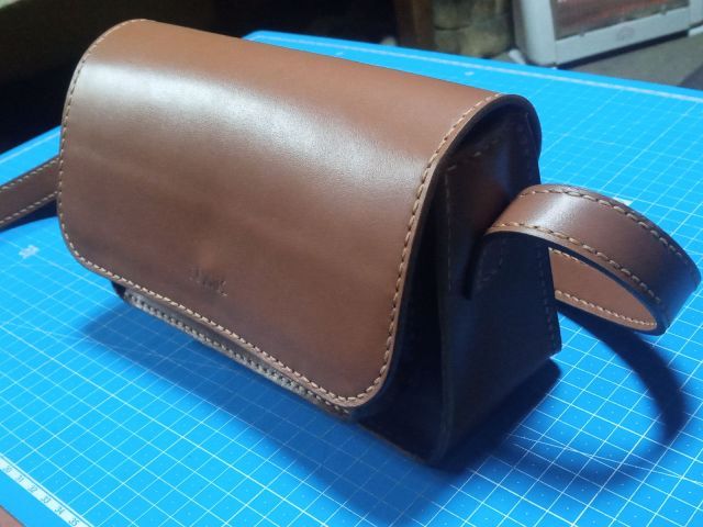 Коричнева шкіряна міні-сумка crossbody з клапаном на магніті та довгим ремінцем, фото на килимку для різання