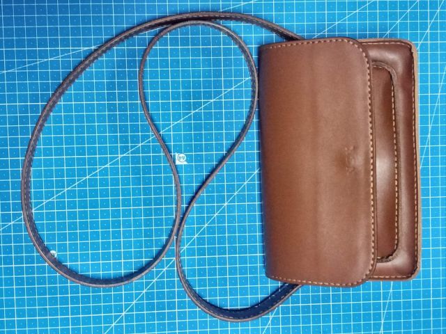 Коричнева шкіряна міні-сумка crossbody з клапаном на магніті та довгим ремінцем, фото на килимку для різання