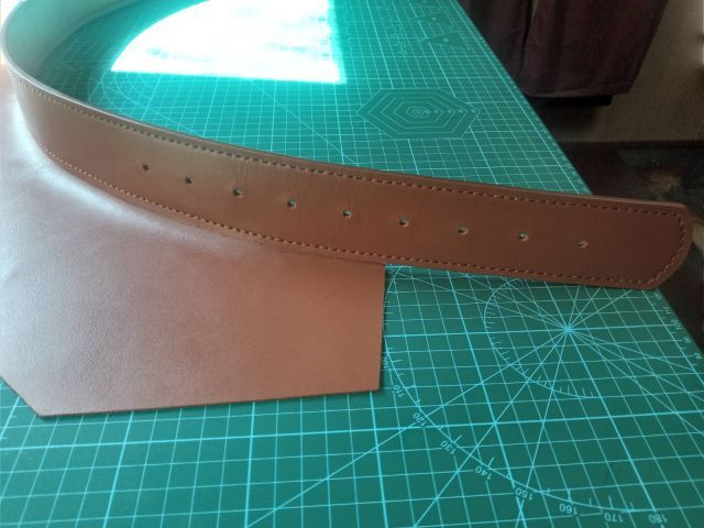 Коньячний шкіряний ремінь ручної роботи з прошитими краями та отворами для регулювання, фото на килимку для різання
