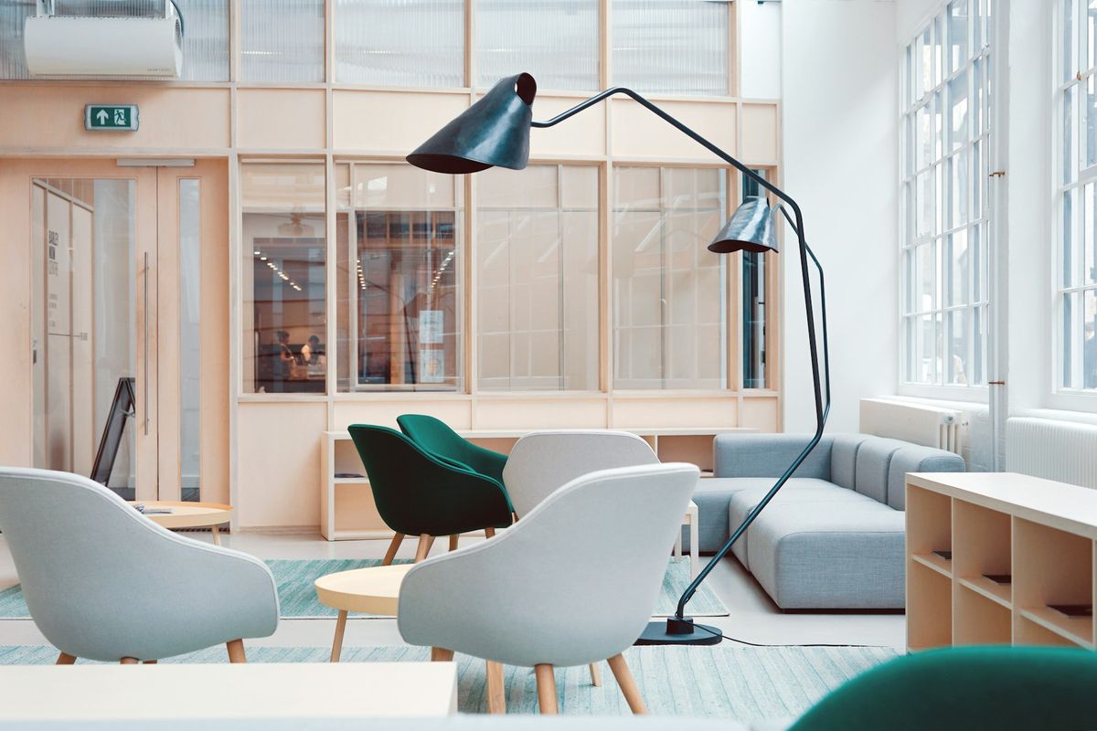 A bright breakout area with armchairs and a floor lamp