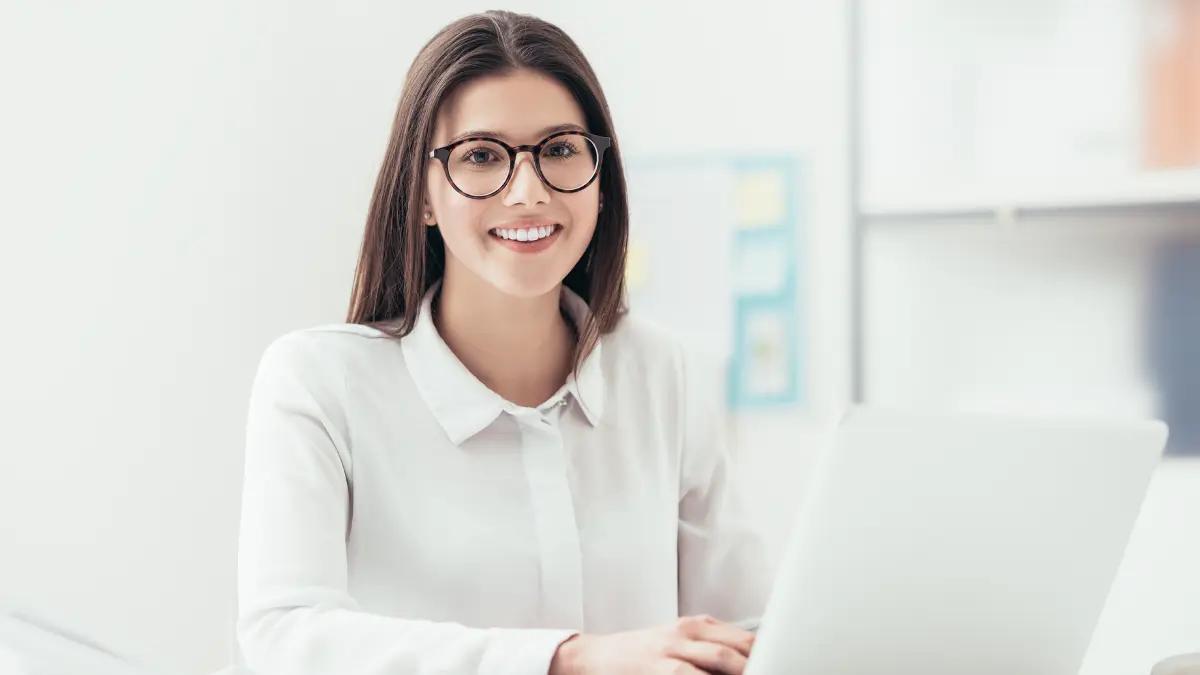 Analyst in glasses working at a laptop in a bright office