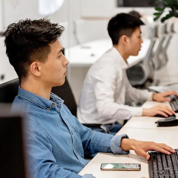 Two analysts working at desktop monitors in an open office