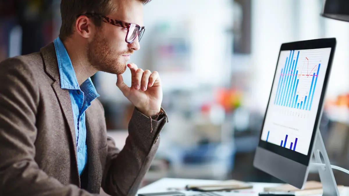 Risk analyst studying a bar chart of vendor metrics on a desktop monitor