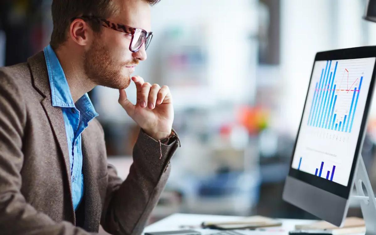 Risk analyst studying a bar chart of vendor metrics on a desktop monitor