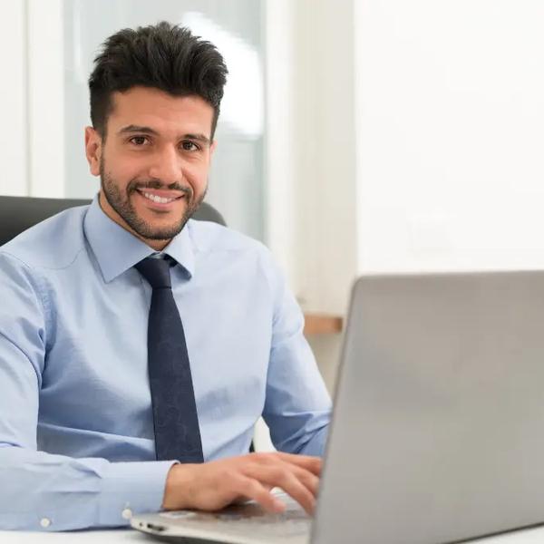 Man in a shirt and tie working at a laptop in an office