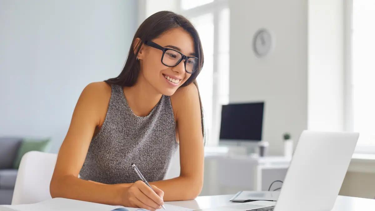 Analyst taking notes beside a laptop in a home office
