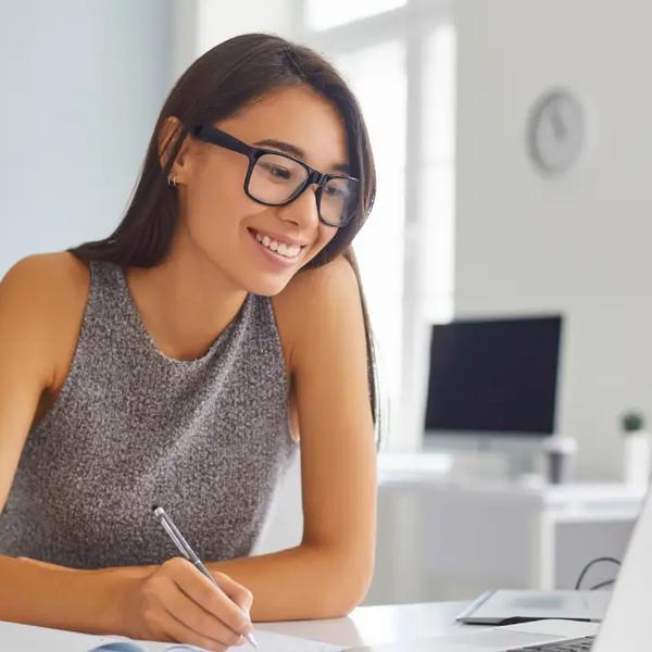 Analyst taking notes beside a laptop in a home office