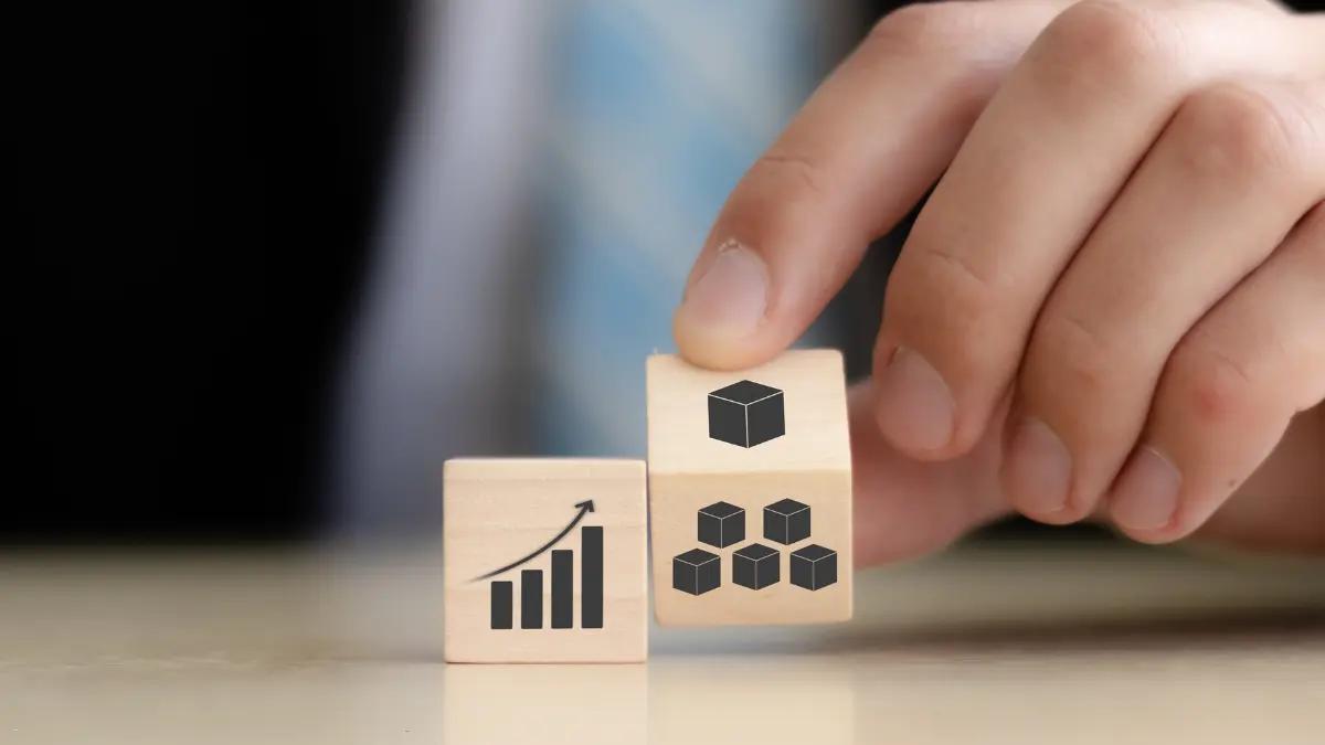 Hand turning wooden blocks printed with a growth chart and a cluster of cubes