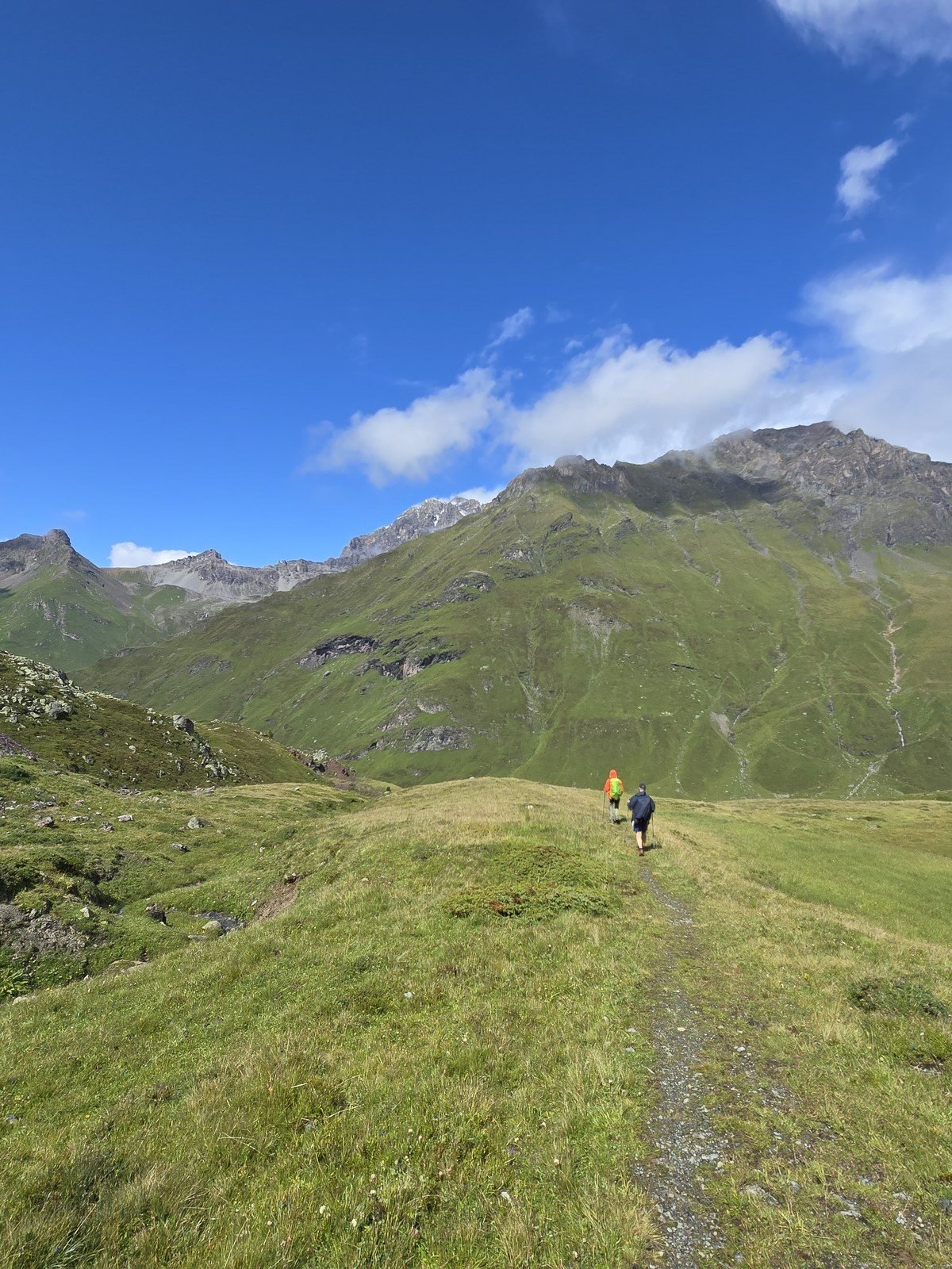 The trail rolling toward the Furschela da Colm under a blue sky