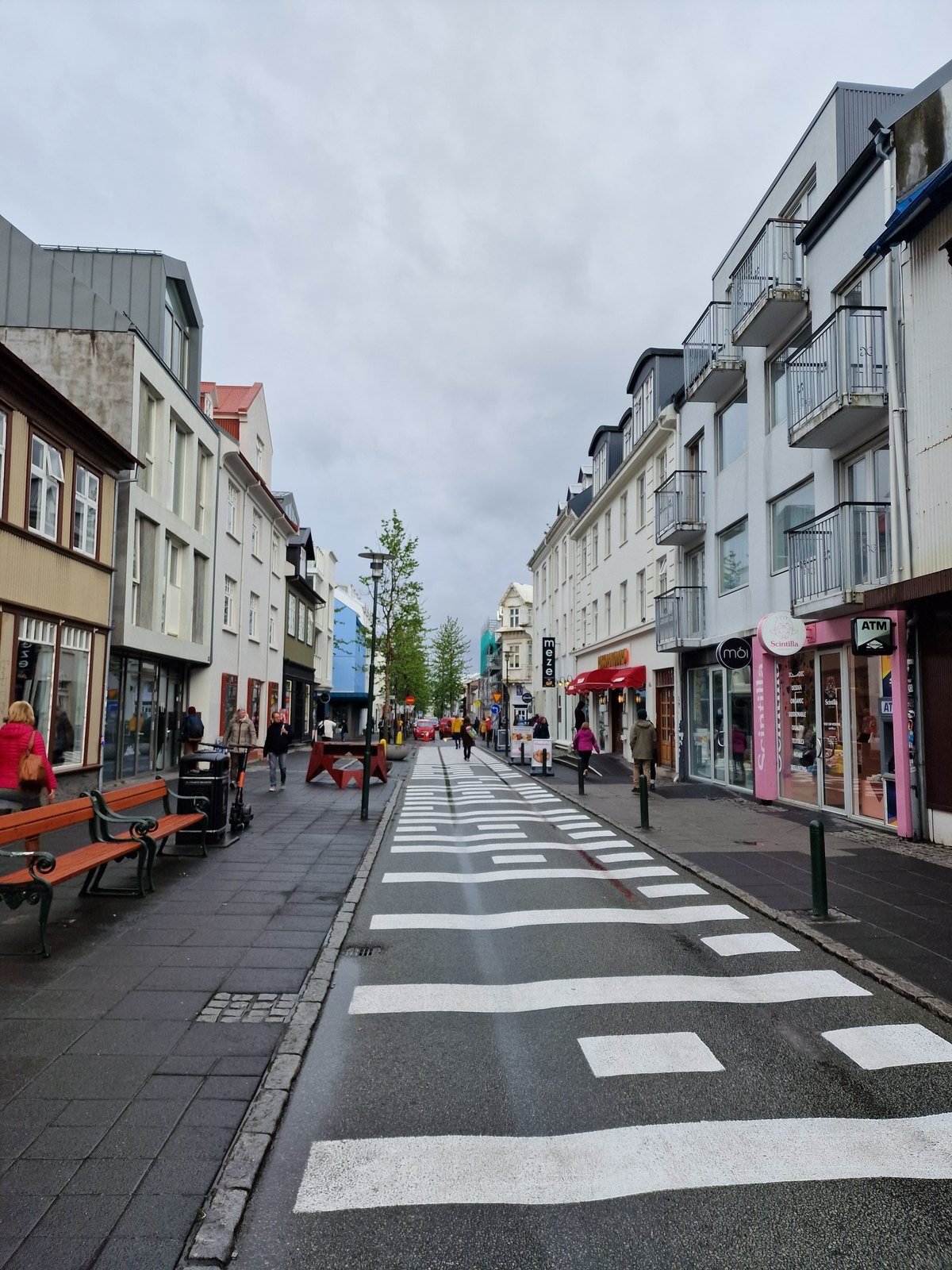 A Reykjavík shopping street with painted shopfronts and a striped crossing