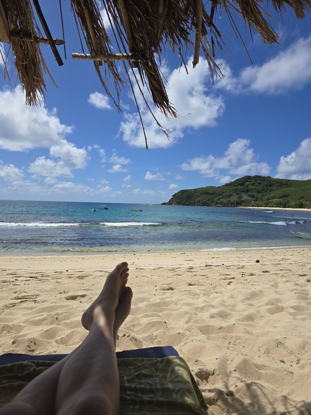 Feet up on a sun lounger over white sand and turquoise shallows