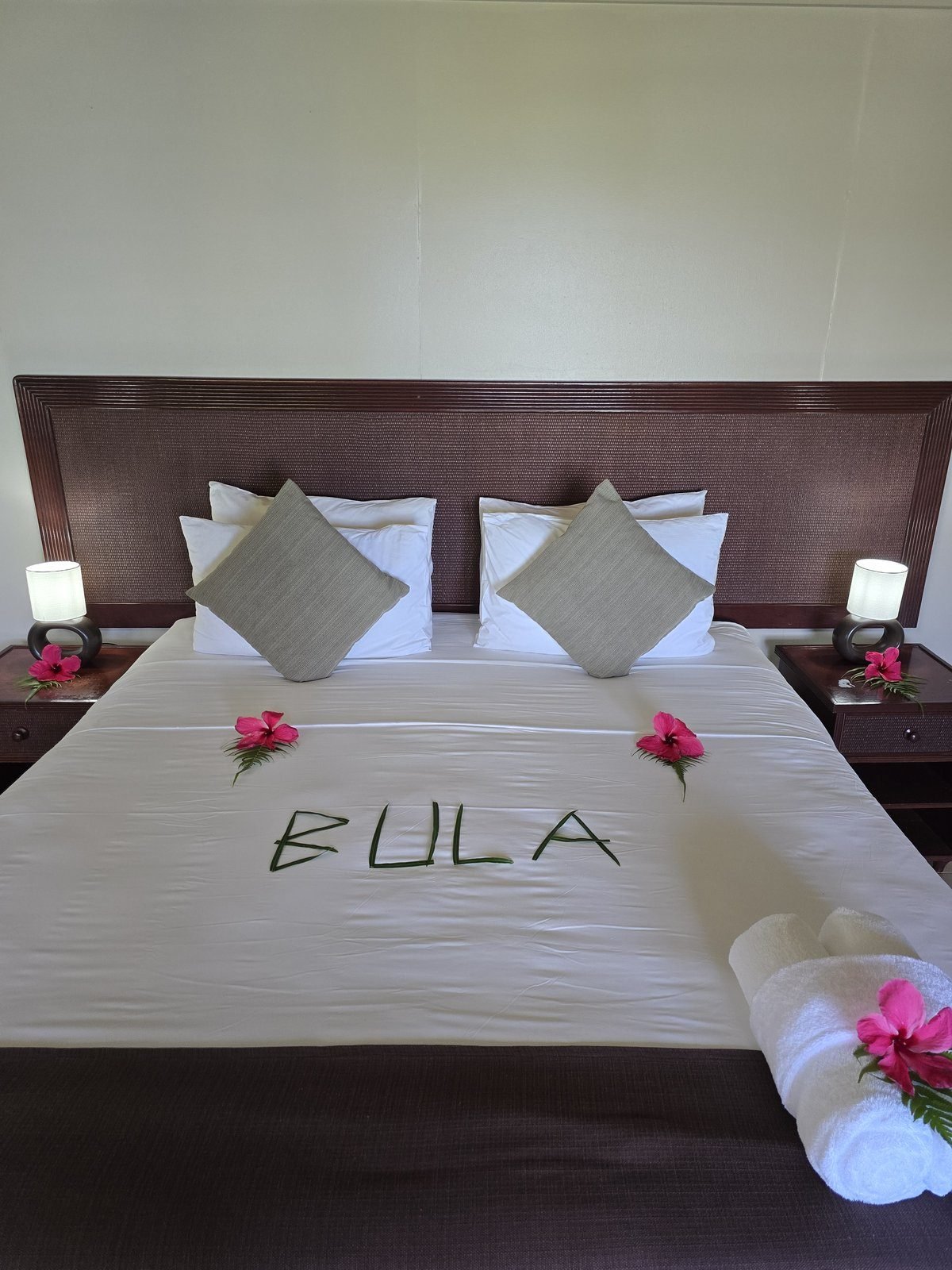 A resort bed made up with BULA spelled in leaves and hibiscus flowers