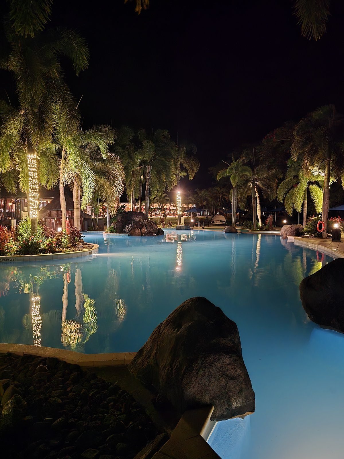 A resort pool under palms after dark