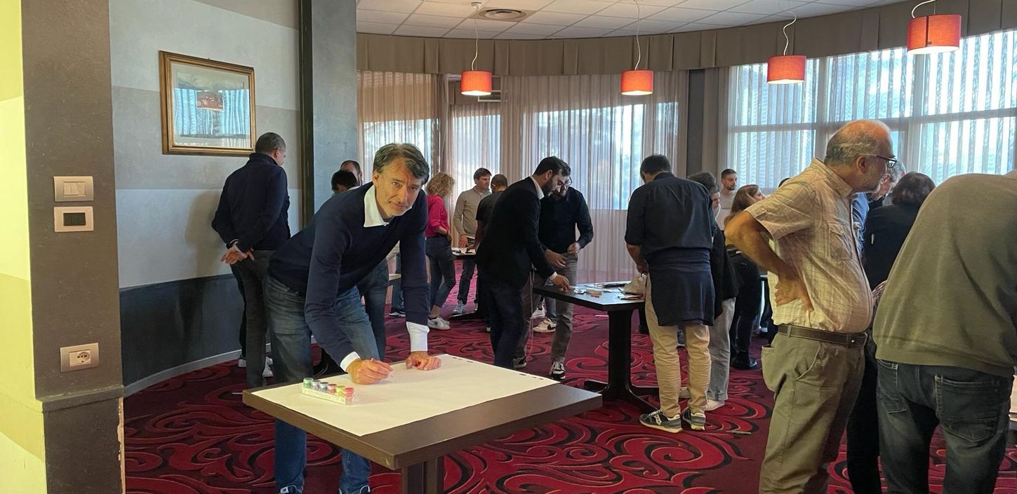 Un gruppo di persone che interagisce attorno a dei tavoli durante una conferenza