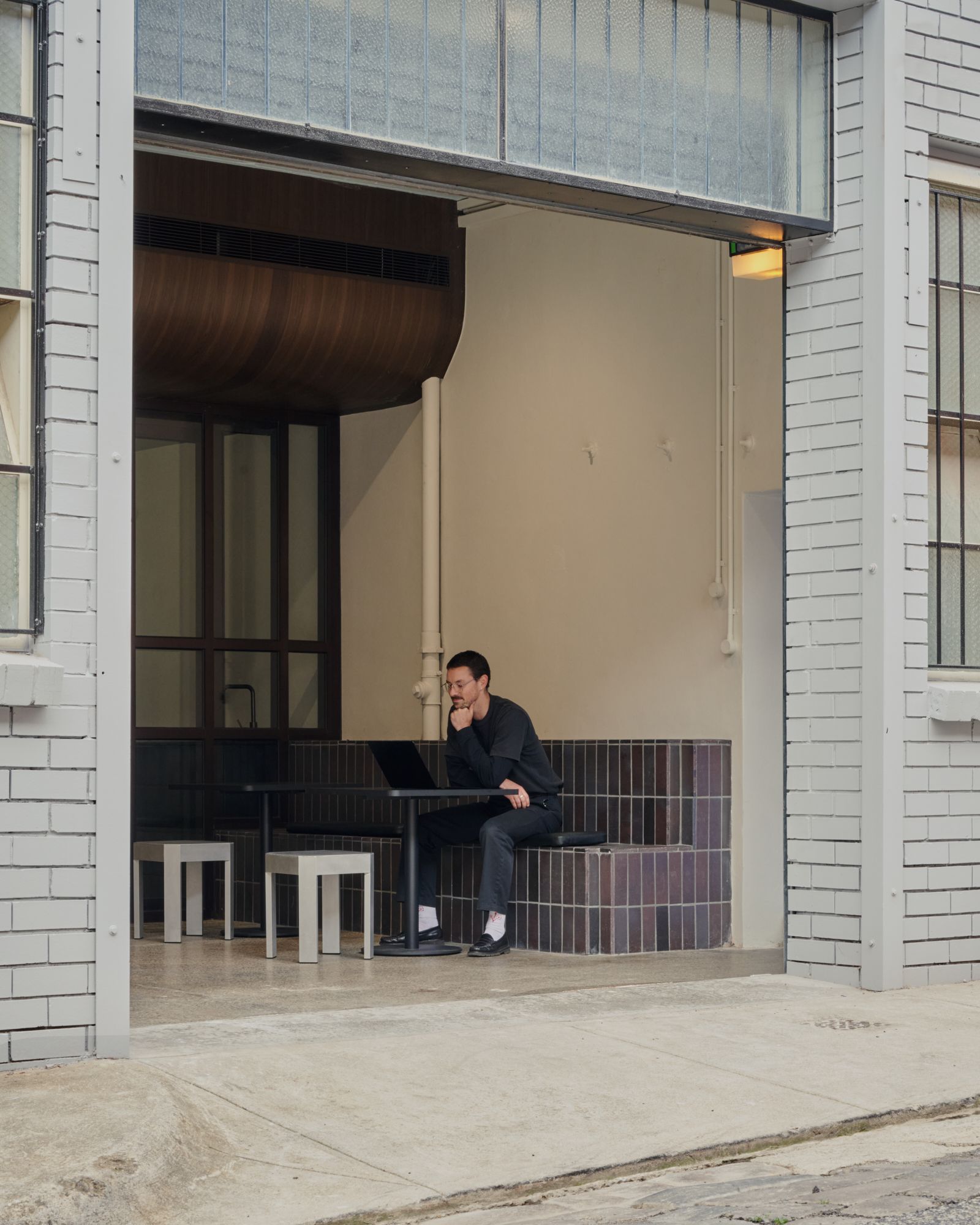 A person sitting on the brick tiered seating looking at a laptop | LSR Workplace by Made For | South Melbourne | Veeral Patel
