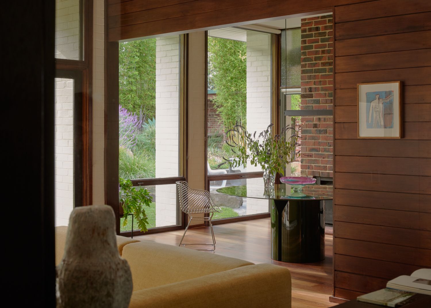 A view into the dinning room of Wildwood featuring a green dining table, NVL, by MDF Italia. A garden view of Wildwood showing the depth of the colonnades. | Wildwood design by Robin Boyd | Vermont, Victoria | Midcentury Architecture | Architectural Photography by Veeral Patel 