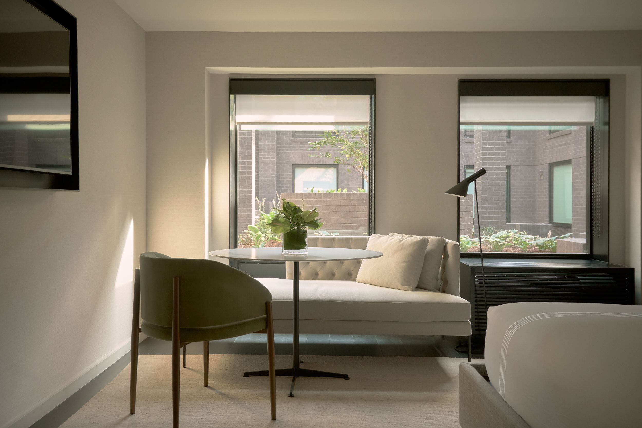 The guest room inside AKA Alexandria. The seating area alongside the glass wall of the restaurant of AKA Alexandria.  | AKA Hotel Alexandria | Alexandria, Virginia, USA | Architecture and Interiors by Lissoni Partners | Photography by Veeral Patel