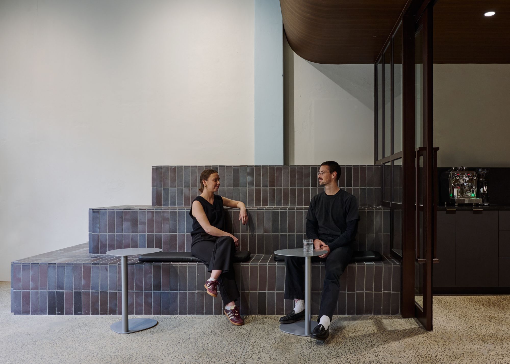 Two people sitting on a brick based tiered sitting inside an office. | LSR Workplace by Made For | South Melbourne | Veeral Patel
