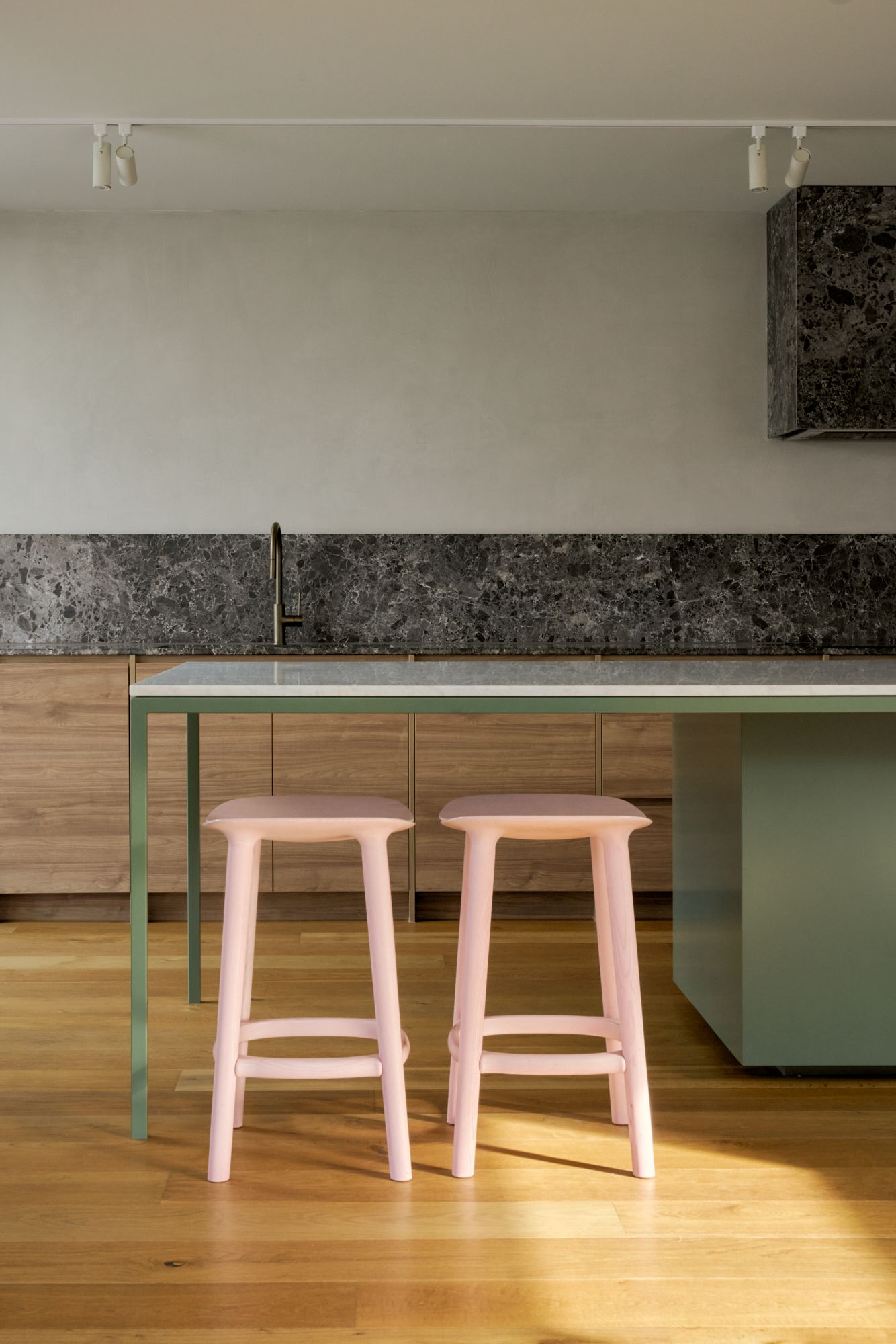 An elevation image of the full length of the kitchen with olive cabinets, pink bar stools and grey marble on the further benchtop and rangehood.| Peavey Residence II by FYC Architects and Snakes & Ladders Projects | Prahran | Veeral Patel