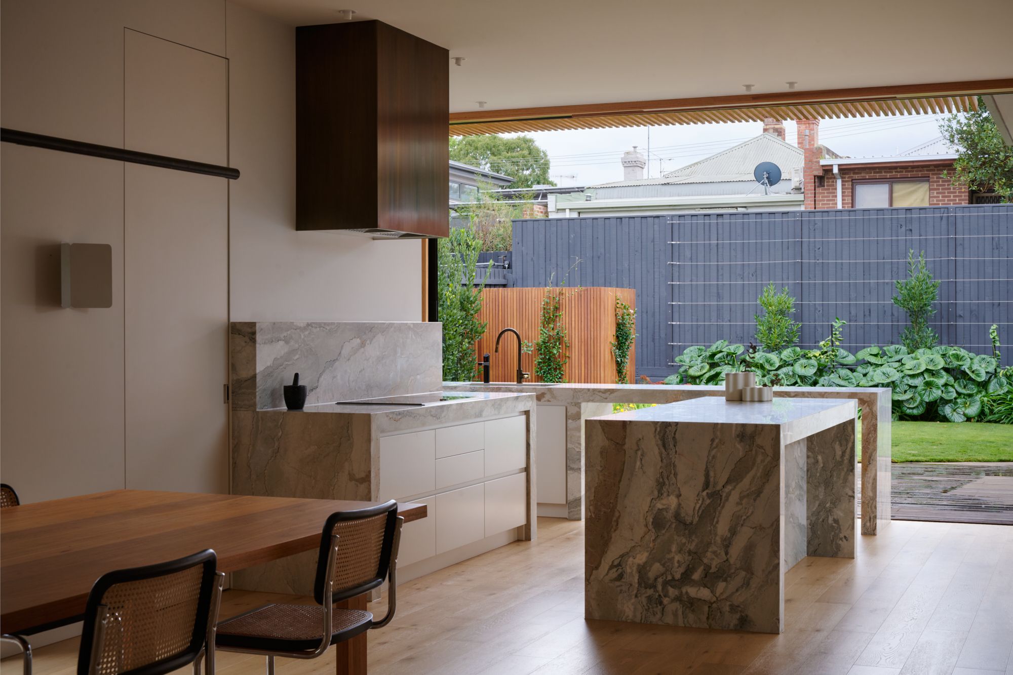 A two point perspective image of the kitchen showing the two islands and a view into the backyard.   | College Street by RCA Studio and Built By Manor | Hawthorn | Veeral Patel