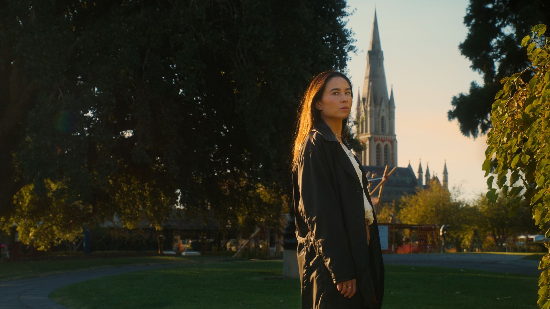 A woman standing in the late afternoon in Brighton Town Hall Gardens.  The International, Brighton developed by Landream & V-Leader | Architecture by Carr | Architectural Film by Veeral Patel