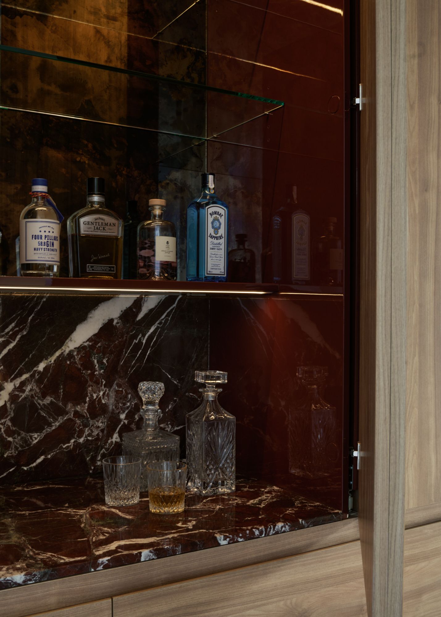 A detailed view into the liqour cabinet. Showing the red marble and liquor bottles with red painted sides.   | Peavey Residence II by FYC Architects and Snakes & Ladders Projects | Prahran | Veeral Patel