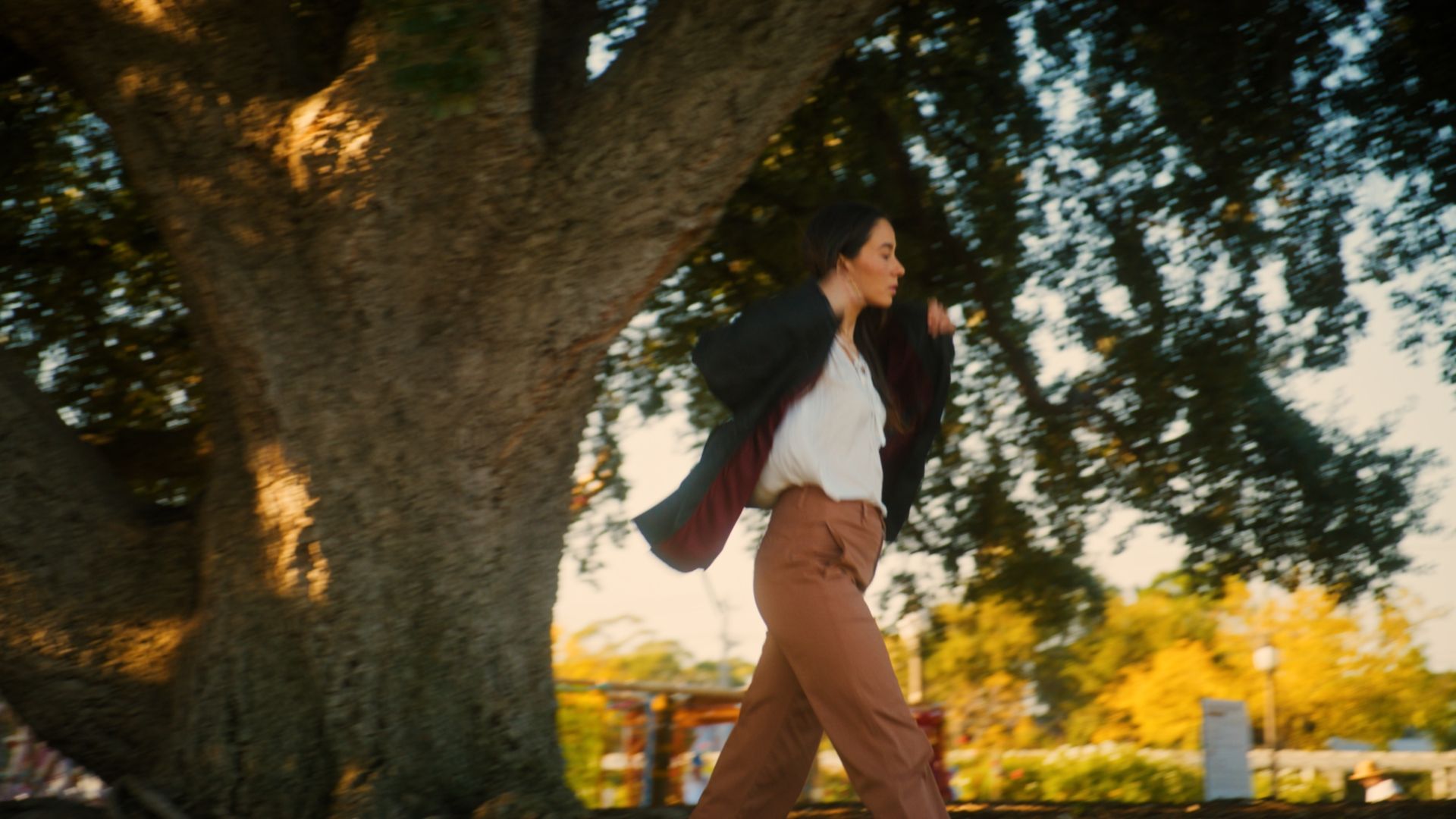 A woman adjusting her jacket as she walks through Brighton Town Hall Gardens.  The International, Brighton developed by Landream & V-Leader | Architecture by Carr | Architectural Film by Veeral Patel