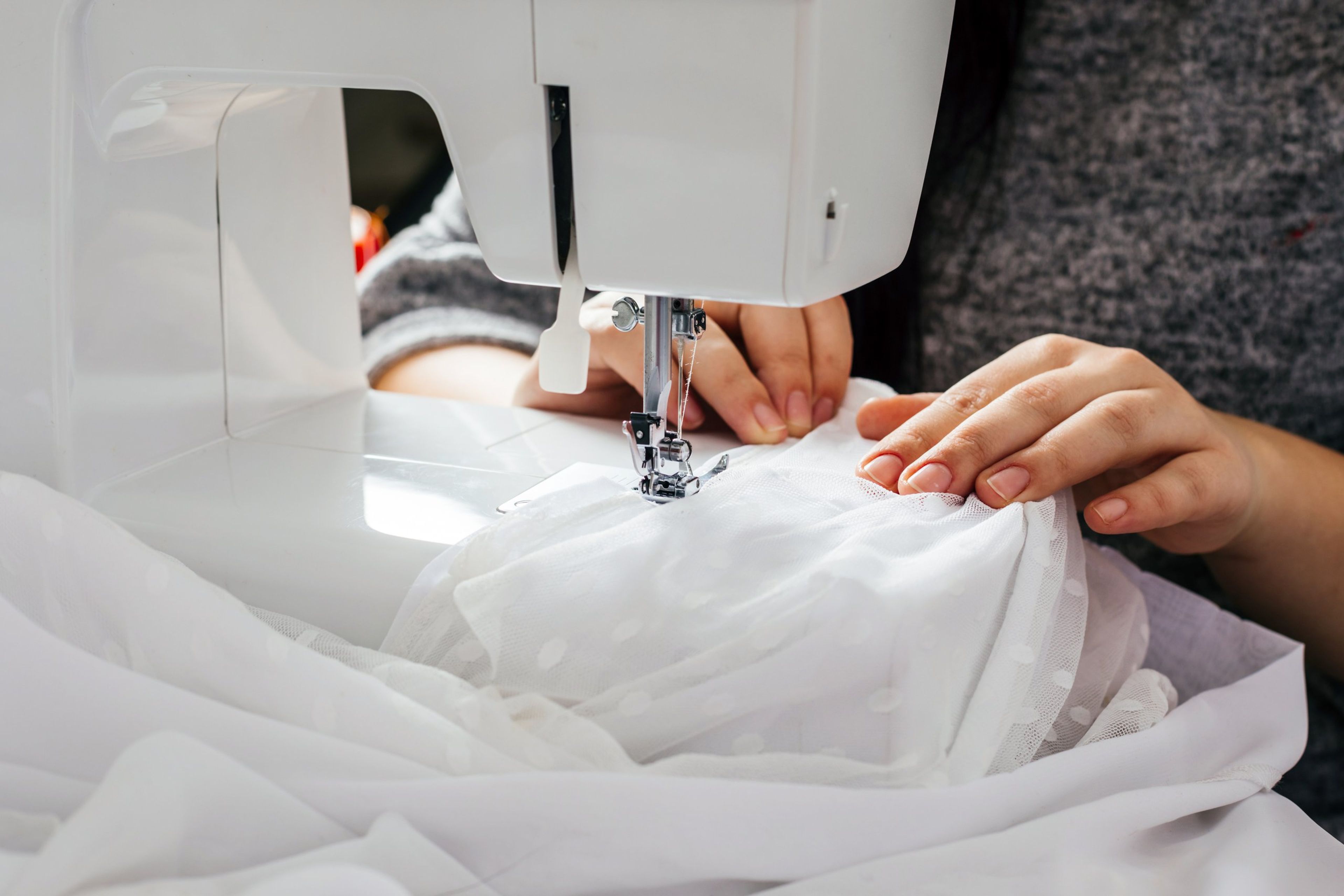 Seamstress guiding bridal fabric through a sewing machine