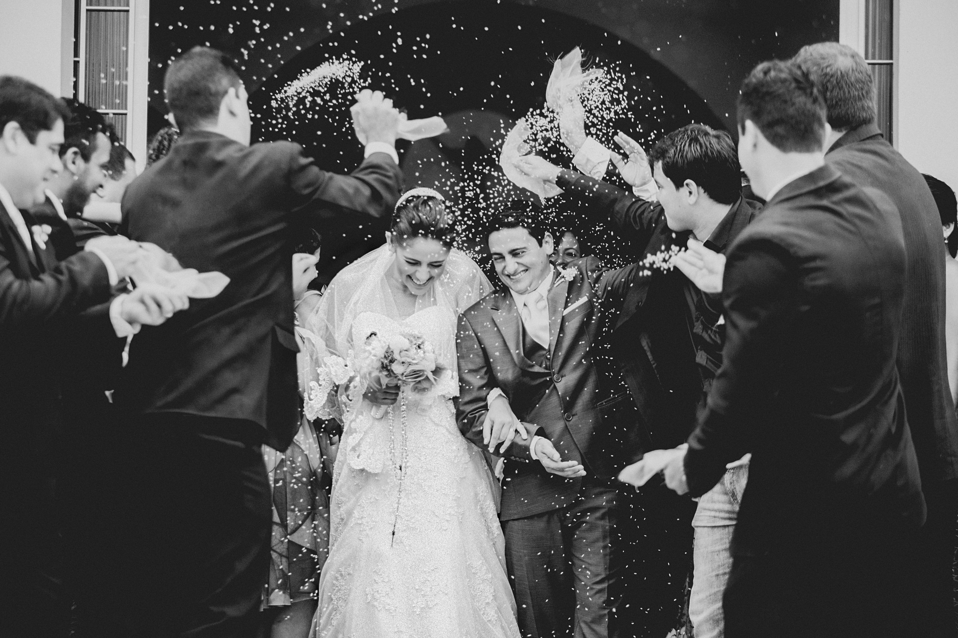 Wedding guests throwing confetti over a newly married couple leaving the ceremony