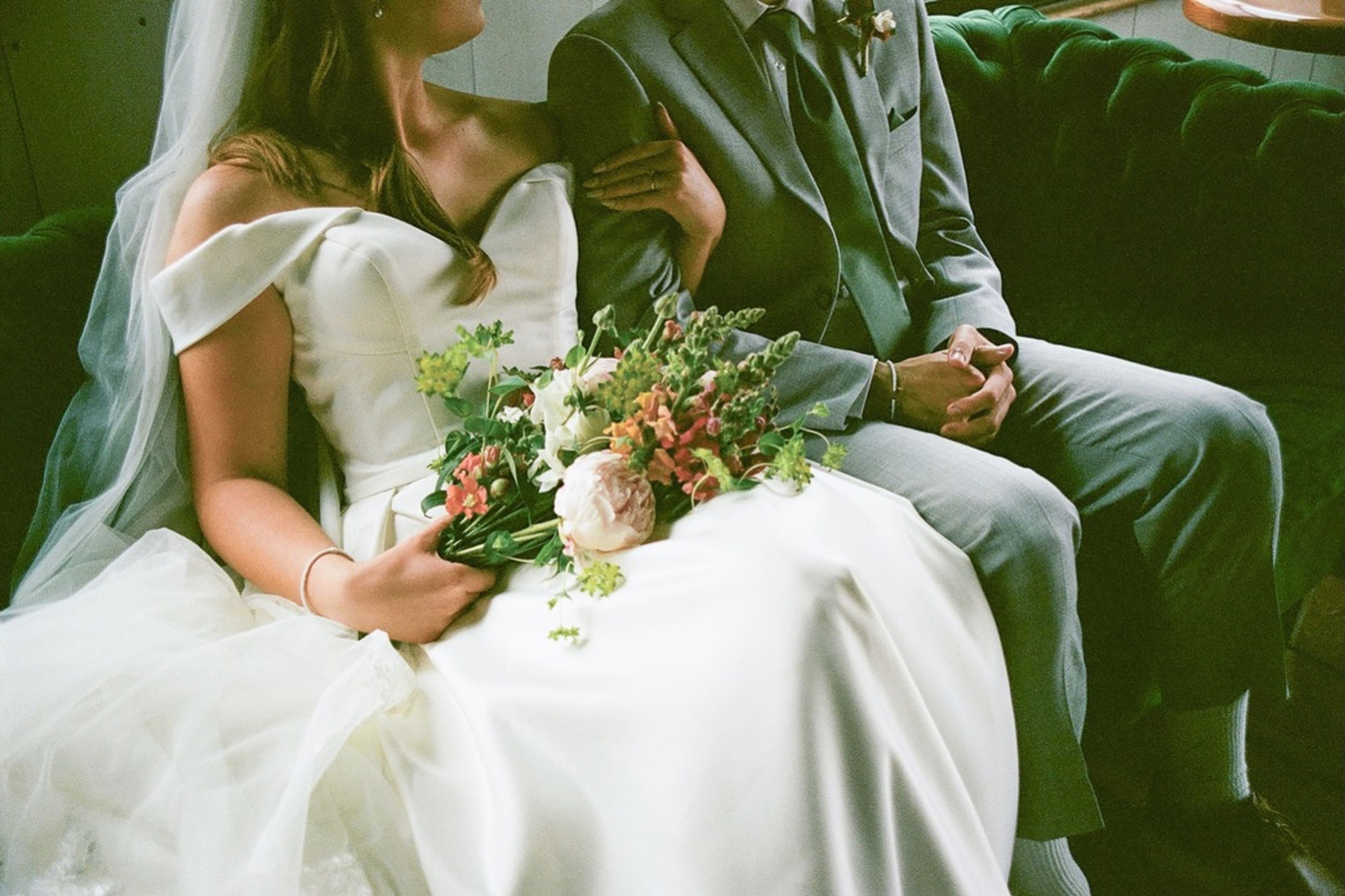 Bride and groom seated together, the bride holding a bouquet of wildflowers