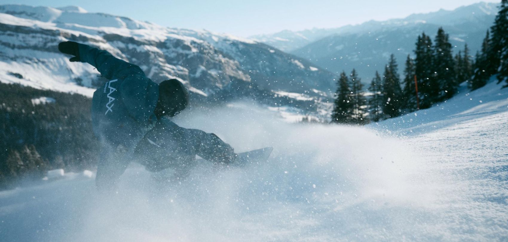 Snowboardlehrer macht ein Trick während dem er eine Kurve fährt