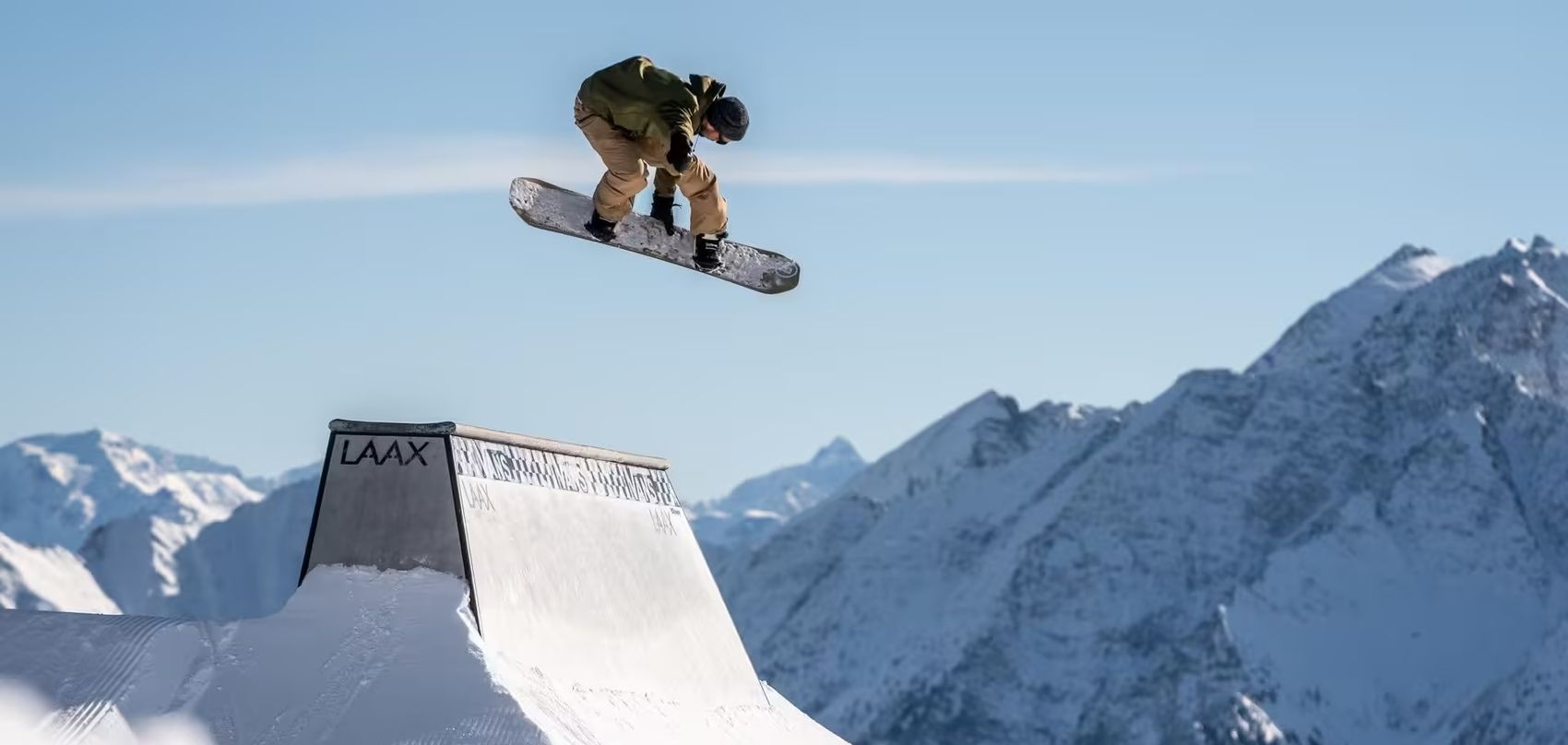 Snowboarder jumps over obstacle