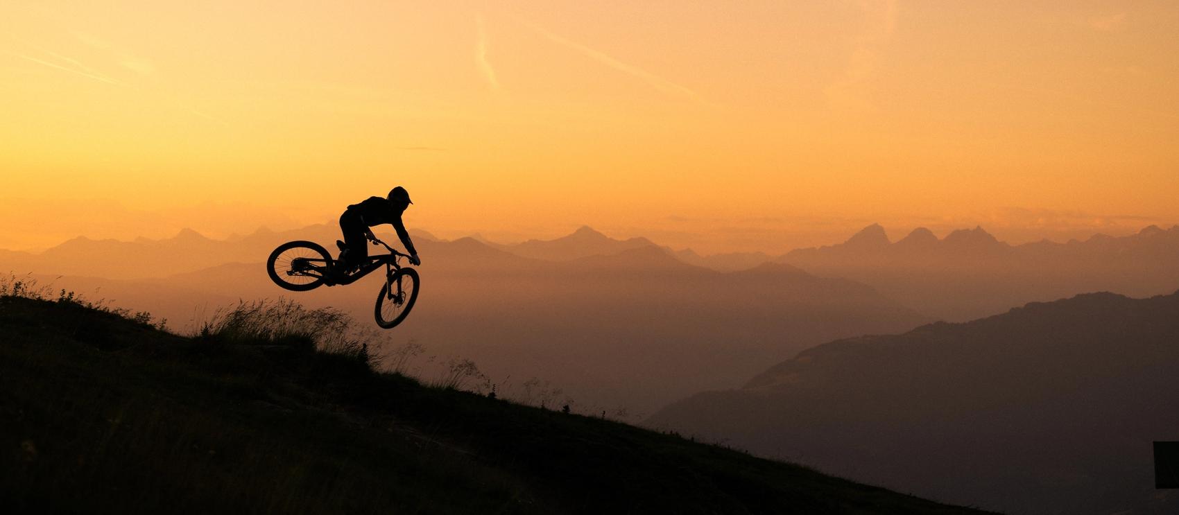 Biker fährt in der Abendsonne über die Wiese
