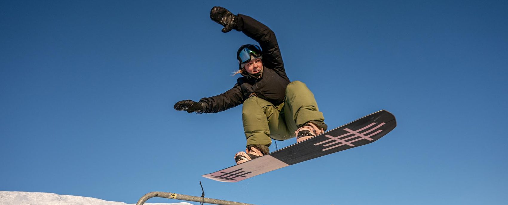 Frau springt mit Snowboard über LAAX Rail